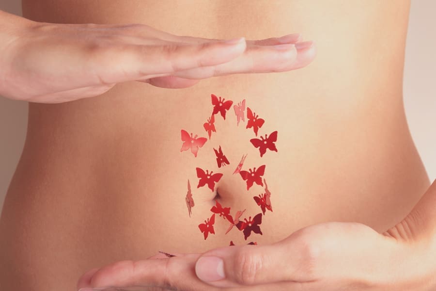 Woman with red flying butterflies between hands. Critical days, woman health or menstruation cycle concept. Close up. Toned